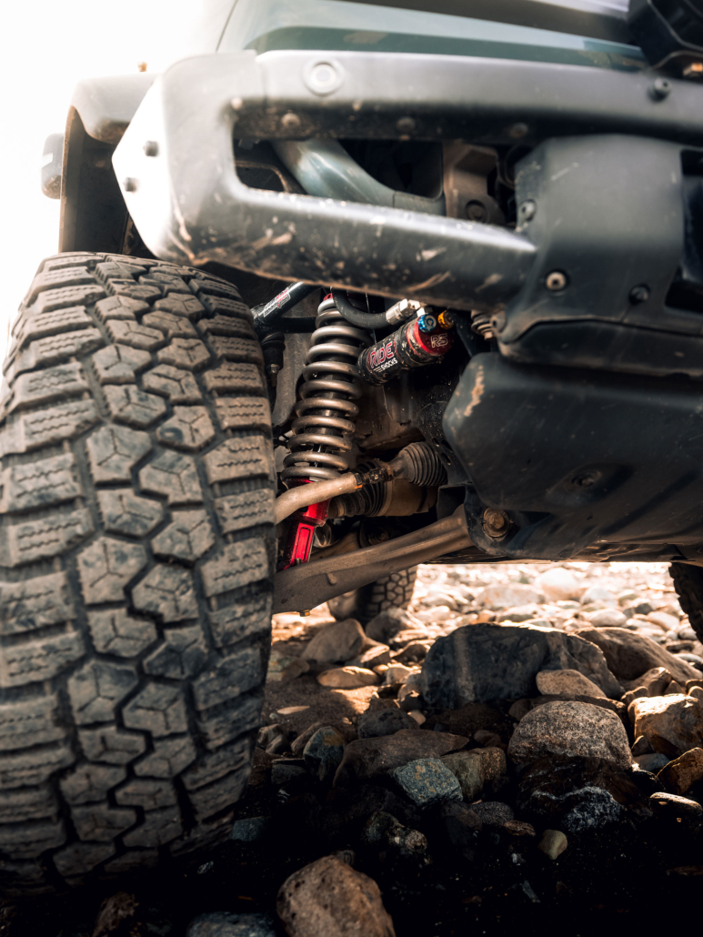 Bronco parked off-road with bright red ride shocks coilovers shown